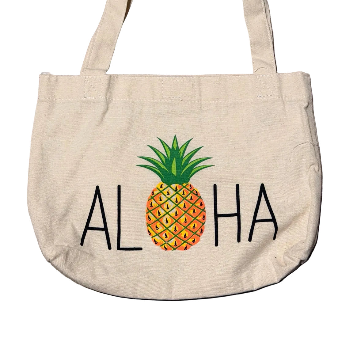 Beige tote bag with pineapple and 'ALOHA' text on a white surface