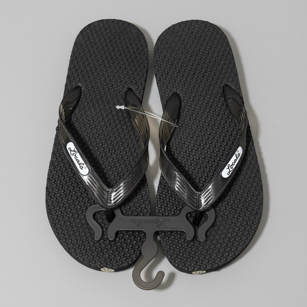 Black flip-flops with a bottle opener on a wooden floor